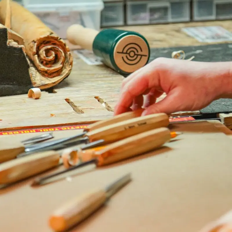 Hand reaching for Schaaf carving chisels on a workbench